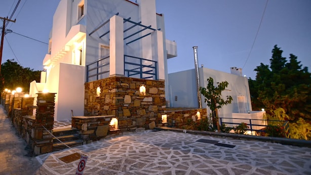 Un edificio moderno con base de piedra y estructura superior blanca, que cuenta con una escalera e iluminación exterior.