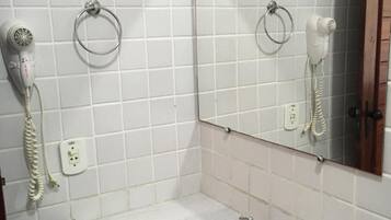 Une salle de bain équipée d’un lavabo, d’un miroir, d’un sèche-cheveux et d’un téléphone.