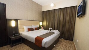 A hotel room with a large bed, a nightstand, a TV, and a curtain. - Florida Al Souq Hotel (Dubai)