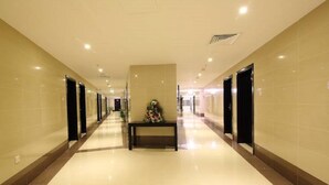 A long, well-lit hallway with a bench and a floral arrangement in the center, flanked by doors on both sides. - Florida Al Souq Hotel (Dubai)