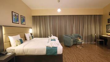 Una habitación de hotel con una cama grande, un escritorio, una silla y un telón de fondo.