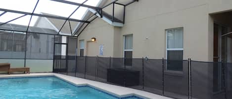 Piscina interna com teto de vidro, cercada por uma grade e um banco próximo à piscina.