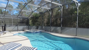A swimming pool with a glass enclosure, lounge chairs, and a hot tub. - Pool Homes Davenport Area by SVV (Davenport)