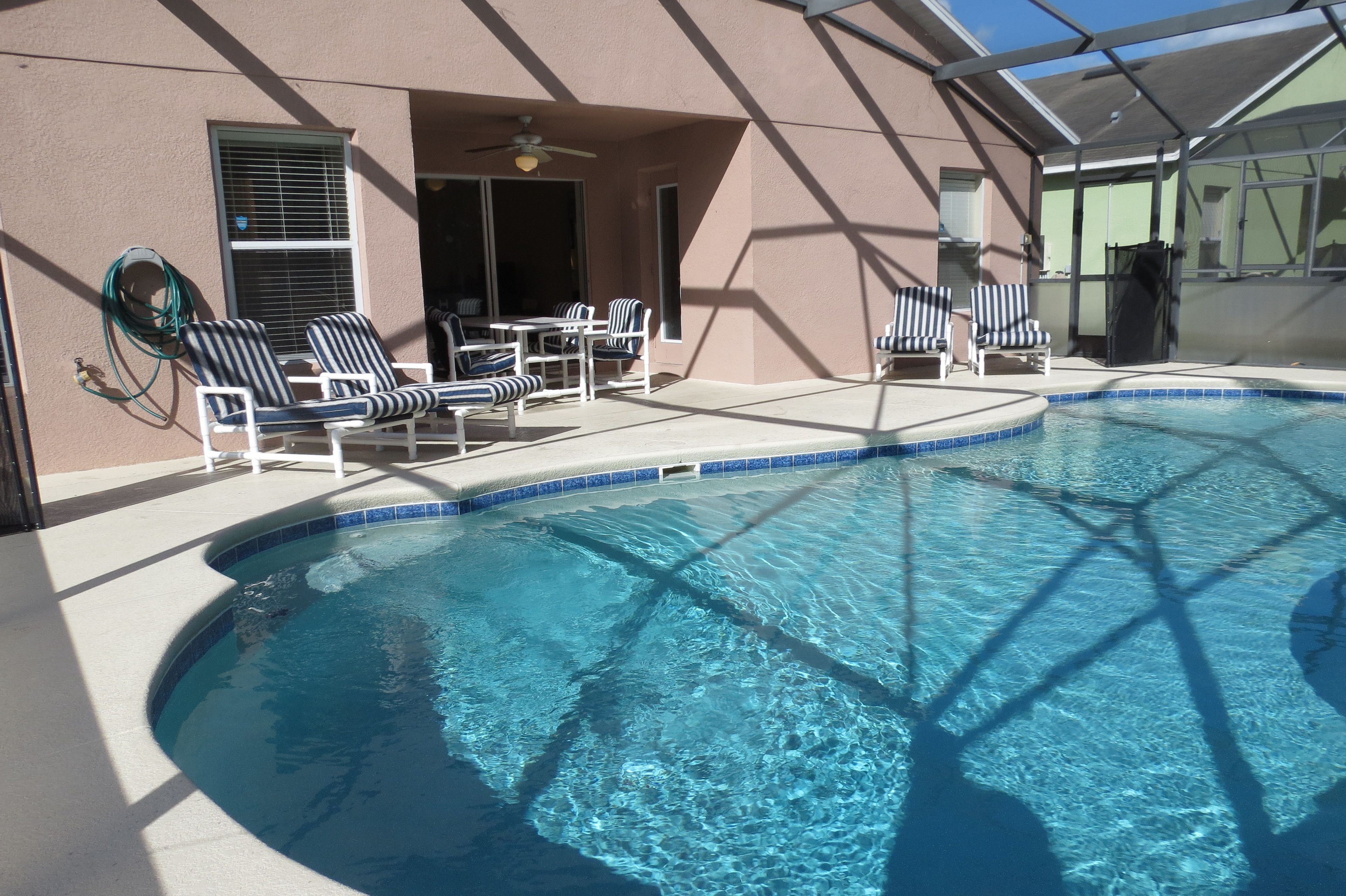 A swimming pool with lounge chairs and a covered patio area.