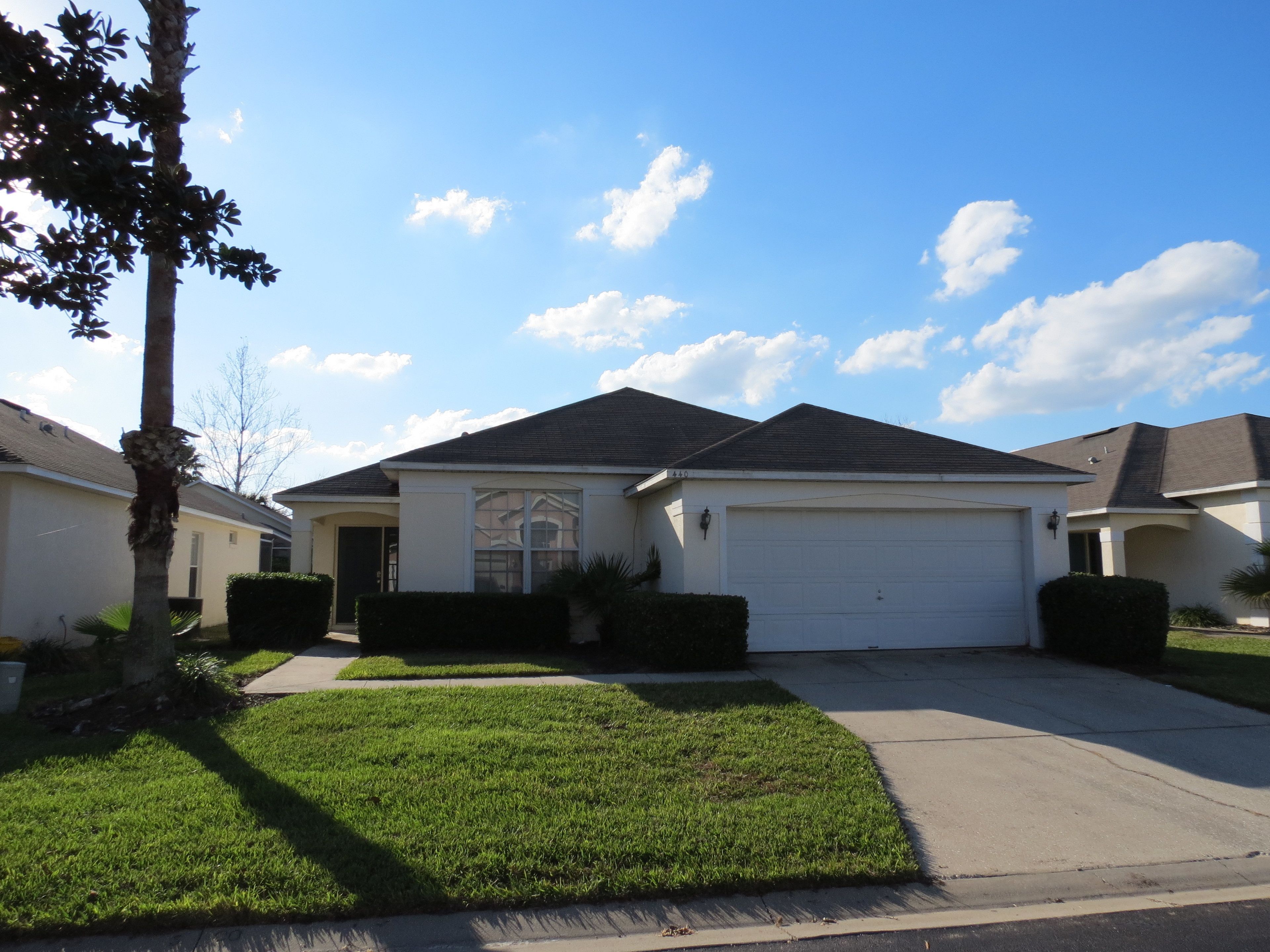A suburban house with a garage, a well-maintained lawn, and a clear sky.