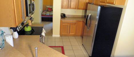 A kitchen with wooden cabinets, stainless steel appliances, and a tiled floor.