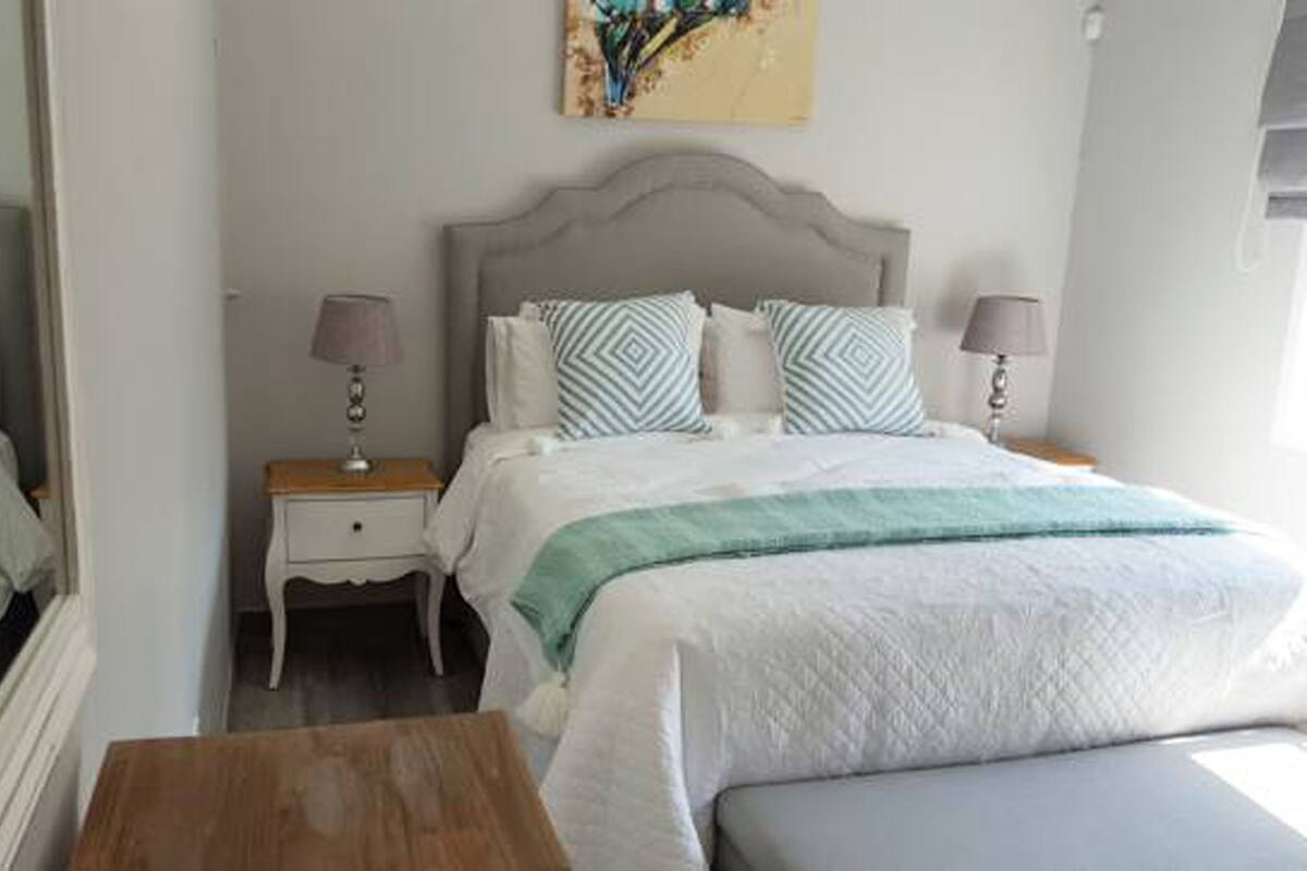 A neatly arranged bedroom with a bed, bedside tables, and a mirror.