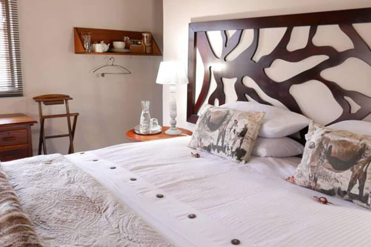 A neatly made bed with patterned pillows, a bedside table with a lamp, and a wooden headboard with a unique design.