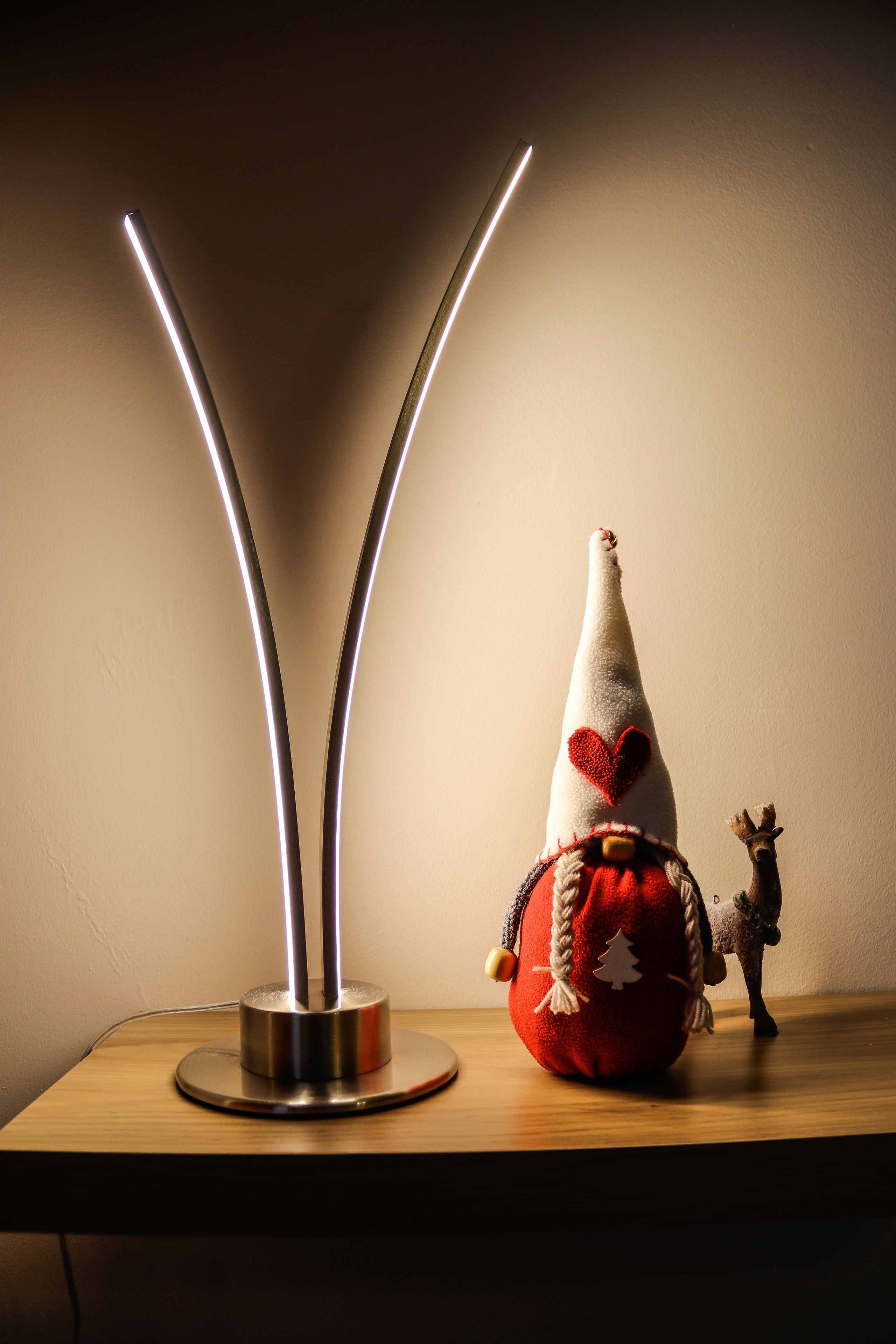 A table with a modern light fixture, a Santa hat, and a small figurine.