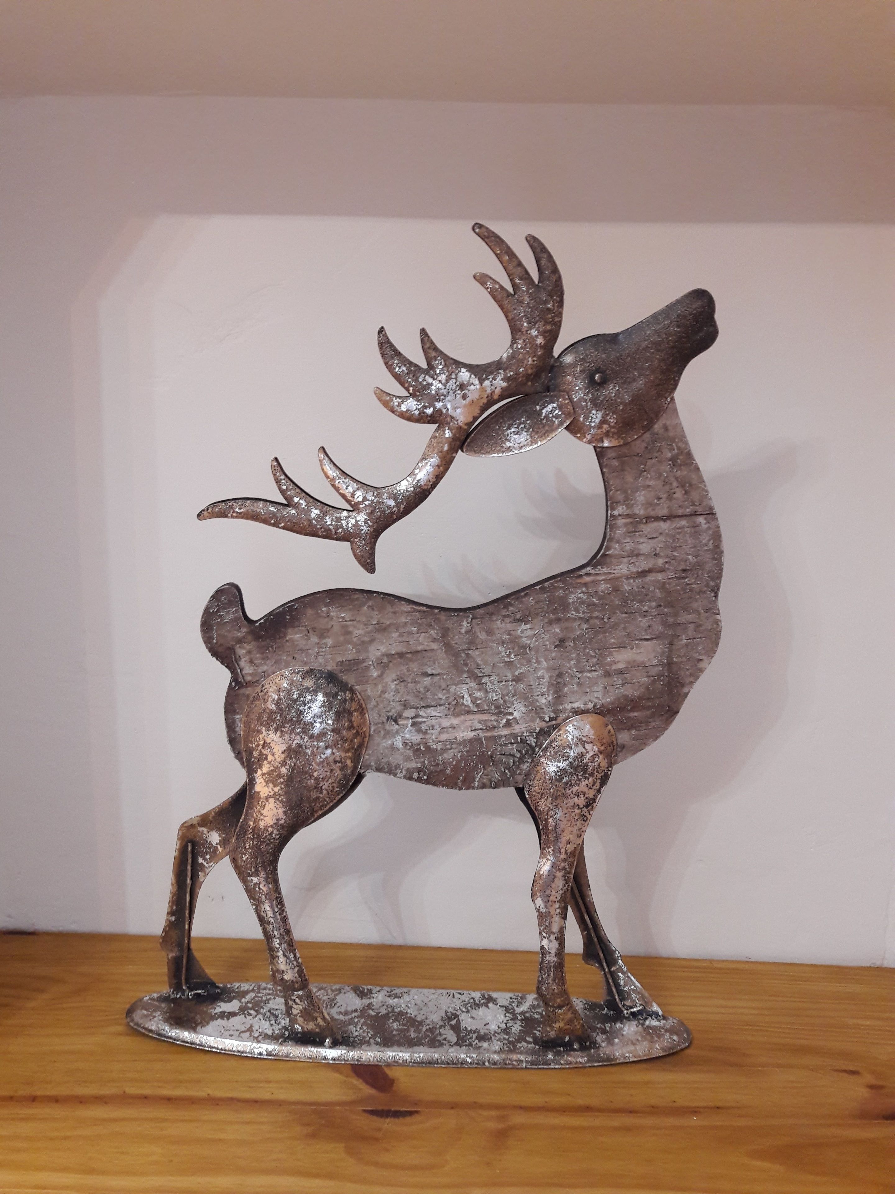 A metal deer sculpture on a wooden base.