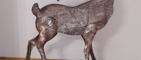 Une sculpture de cerf en métal, montée sur un socle en bois.