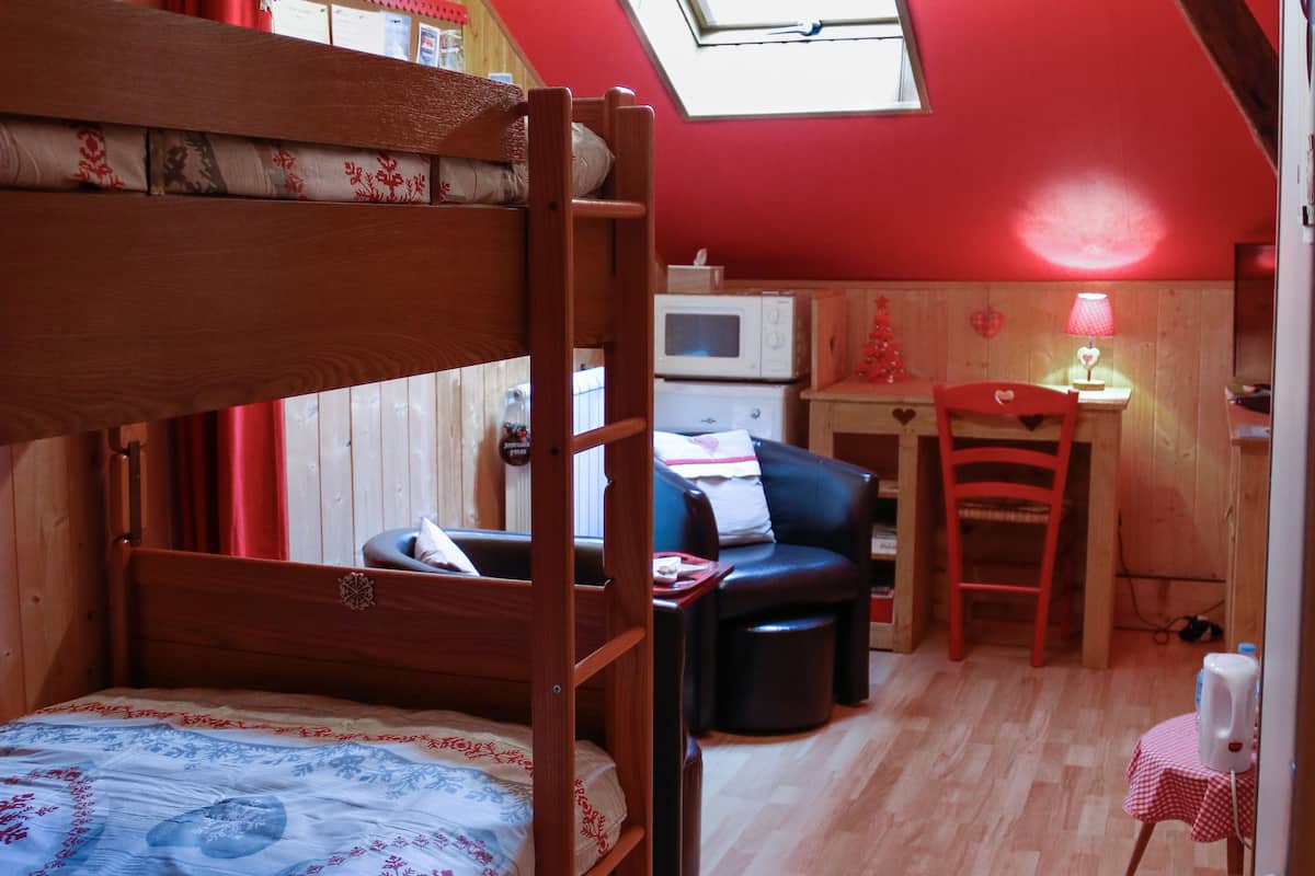 Une pièce confortable avec un lit superposé, un bureau, une chaise et une petite table.