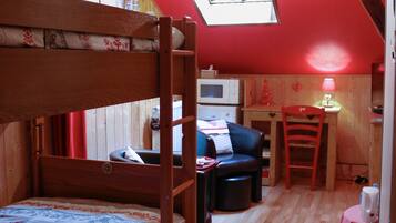 A cozy room with a bunk bed, a desk, a chair, and a small table.