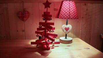 A wooden table with a red and white checkered lamp, a small Christmas tree, and a heart-shaped decoration on the wall.