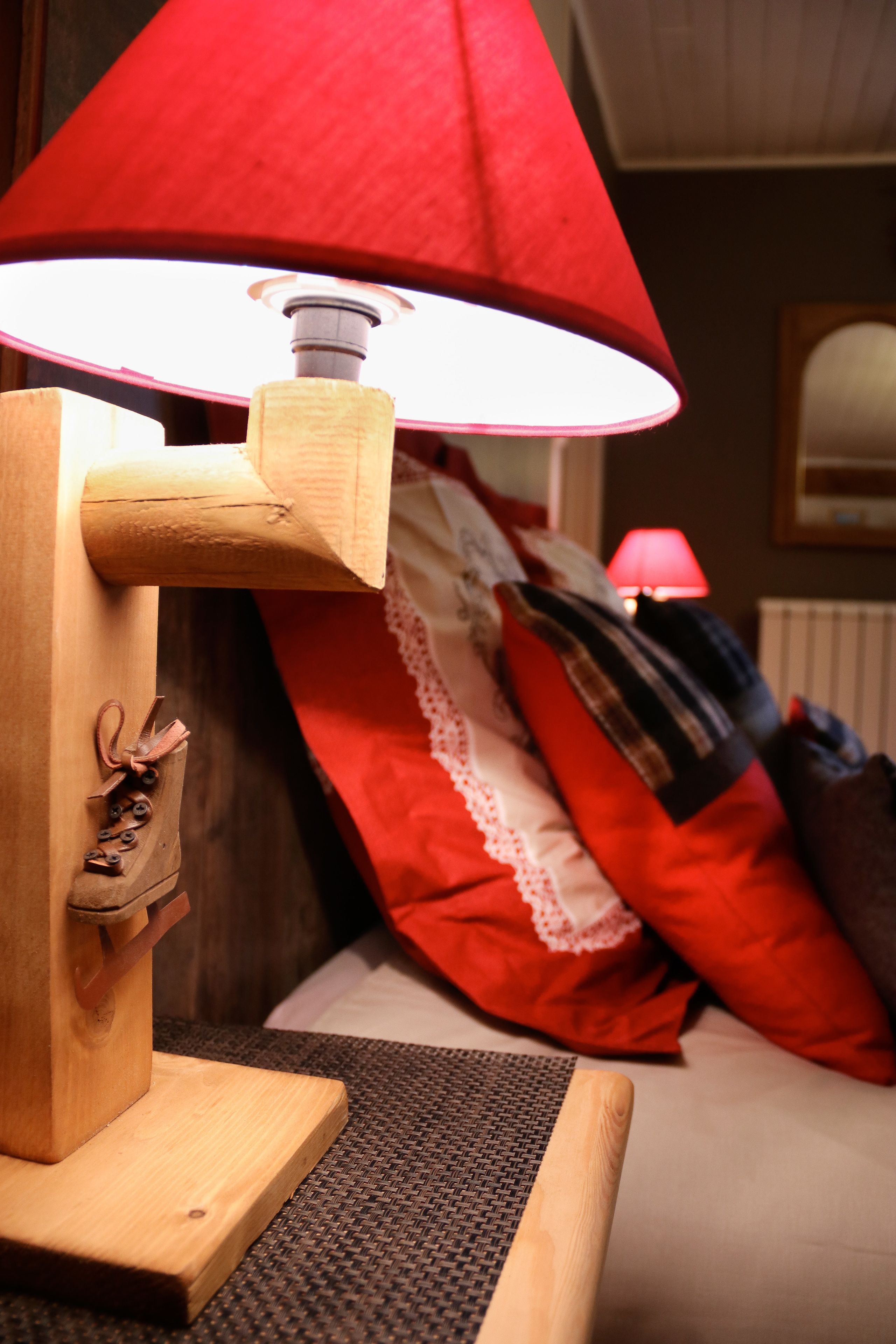 A wooden lamp with a red lampshade on a table.