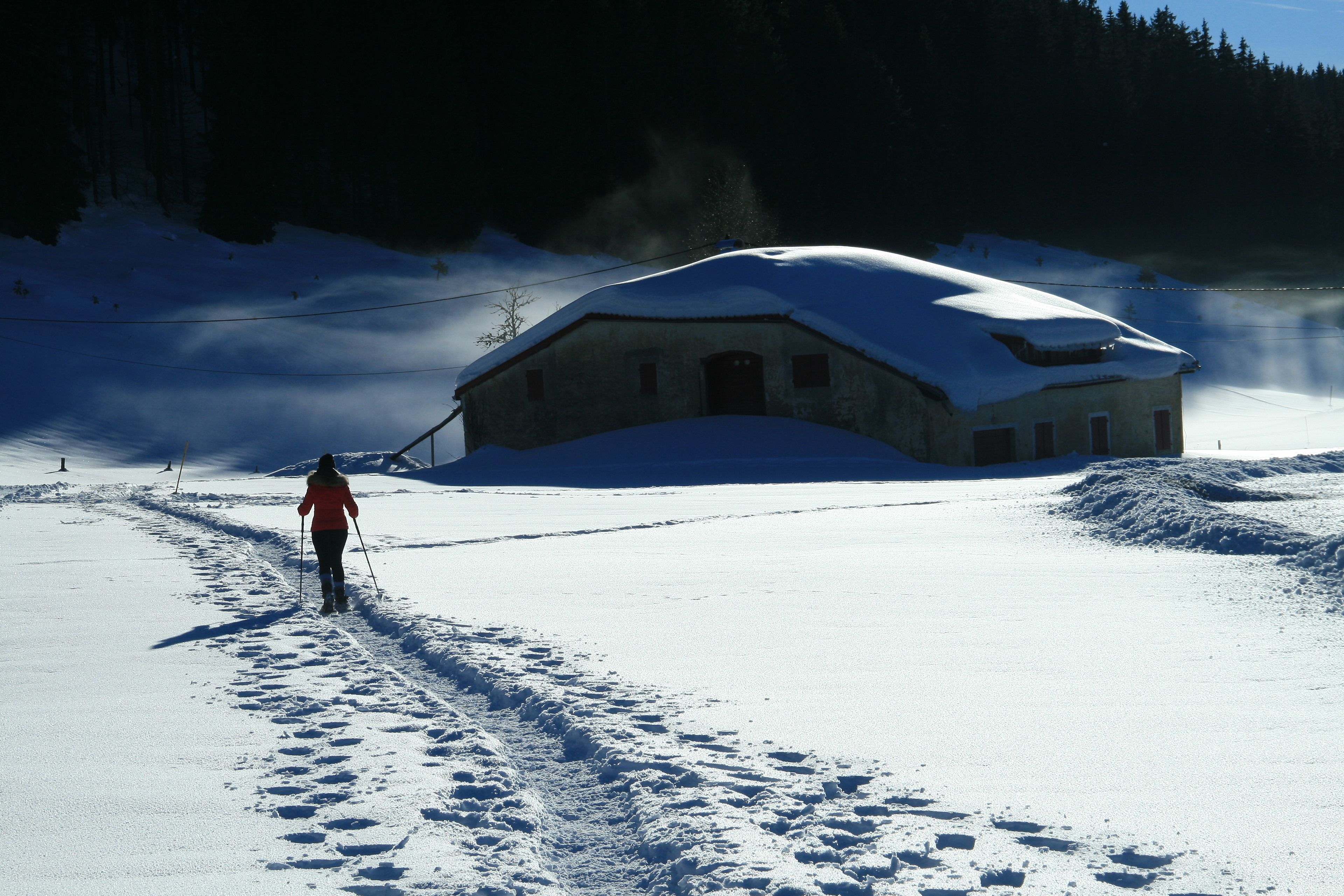 Un paysage enneigé avec un bâtiment et une personne qui fait du ski.