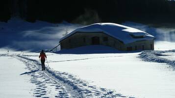 Un paysage enneigé avec un bâtiment et une personne qui fait du ski.