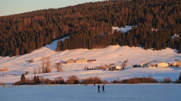 A snowy landscape with a few houses and people on a frozen lake.