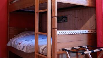 Una cama litera con estructura de madera, un estante pequeño y una escalera.