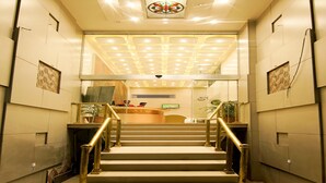 A staircase with a handrail leading to a reception area. - Hotel Amrta (Nagpur)