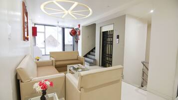 A modern living room with a sofa set, a coffee table, and a vase of flowers. There is a staircase leading to another level.