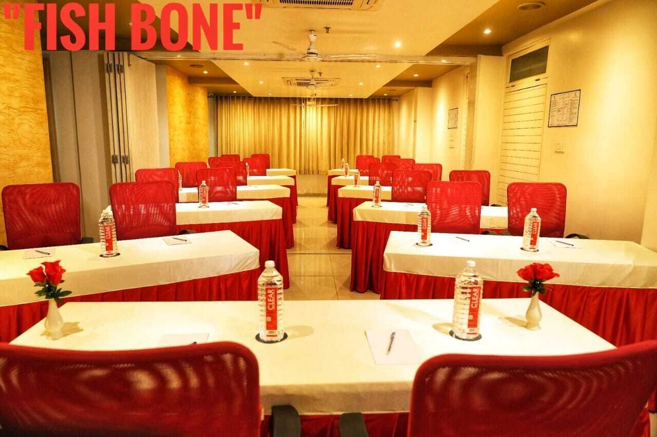 A conference room with red chairs and white tables, each with a bottle of water and a rose vase.