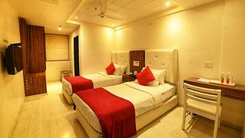 A hotel room with two beds, a desk, and a chair.