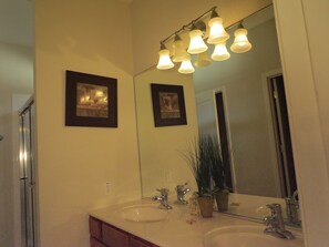 A bathroom with two sinks, a large mirror, and a light fixture above the mirror. - Deluxe Homes with Private Pool by SVV (Davenport)