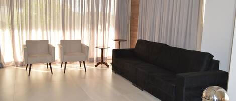 Ein modernes Wohnzimmer mit einem schwarzen Sofa, zwei Sesseln, einem kleinen Tisch und einem Mülleimer.