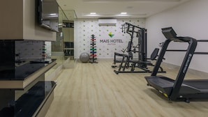 Une salle de sport équipée de tapis de course, d’appareils de musculation et de ballons d’exercice.