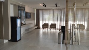 Un hall d’hôtel spacieux au design moderne, comprenant un grand espace salon, un réfrigérateur et une poubelle.