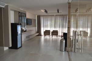 Un amplio vestíbulo de hotel con diseño moderno, que incluye una zona de estar grande, un refrigerador y un cubo de basura.