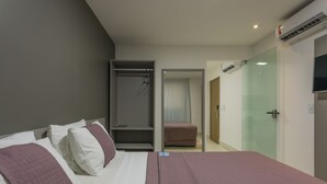 Une chambre d’hôtel comprenant un lit, un dressing, une porte vitrée et un appareil de climatisation.