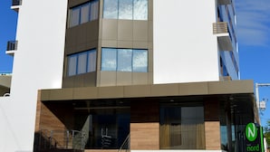 Un bâtiment moderne à plusieurs étages, doté d’une façade plane, de grandes fenêtres et d’une entrée bien visible avec un escalier.