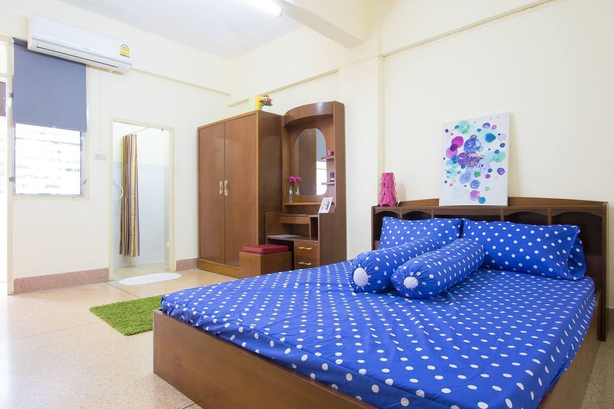 A bedroom with a bed, wardrobe, and artwork on the wall.