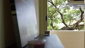 A window view of a tree and a wall-mounted air conditioning unit. - Homeplace Residence (Bangkok)