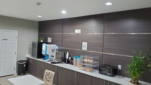 A modern kitchen with a coffee machine, microwave, and storage cabinets. - Haven Inn & Suites Willowbrook (Houston)