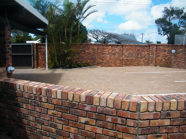 A brick wall with a flat roof and a paved area in front.