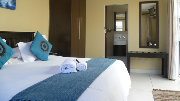 Una habitación de hotel con cama, armario, baño y escritorio.