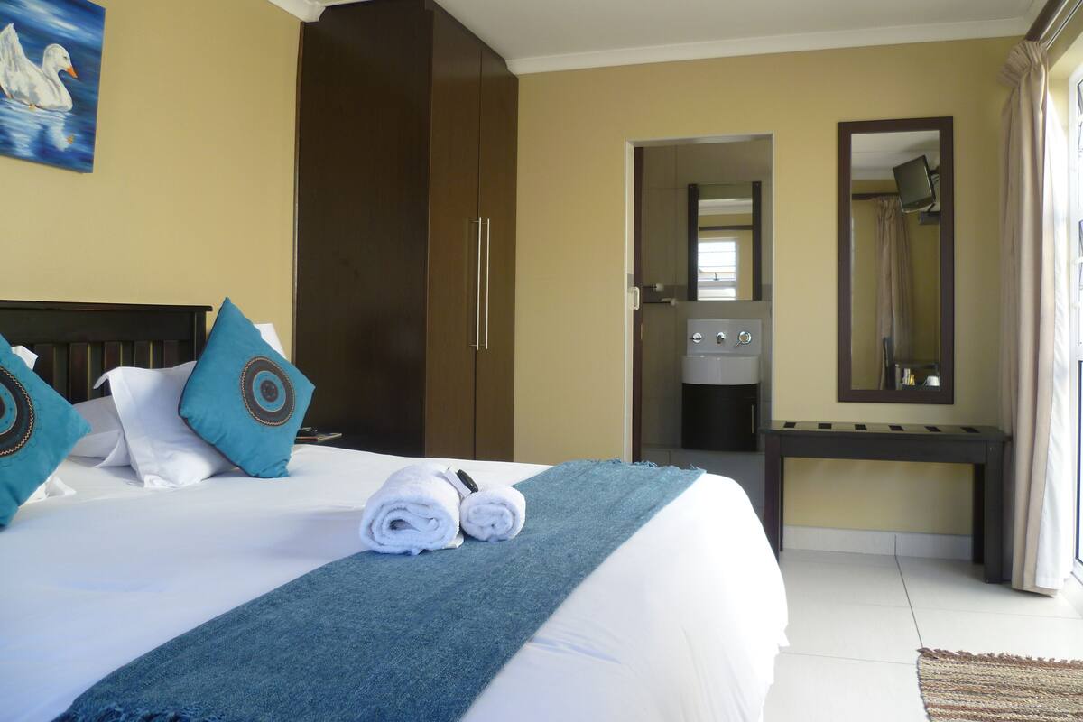 A hotel room with a bed, a wardrobe, a bathroom, and a desk.