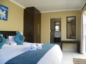 A hotel room with a bed, a wardrobe, a bathroom, and a desk.