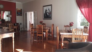 Un comedor con muebles de madera, un cuadro en la pared y un ventanal con cortinas rojas.