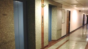 Pasillo con ascensores, una puerta con el número 7 y una lámpara fijada a la pared.