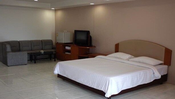 Una habitación de hotel con cama, sofá, televisión y una mesita.