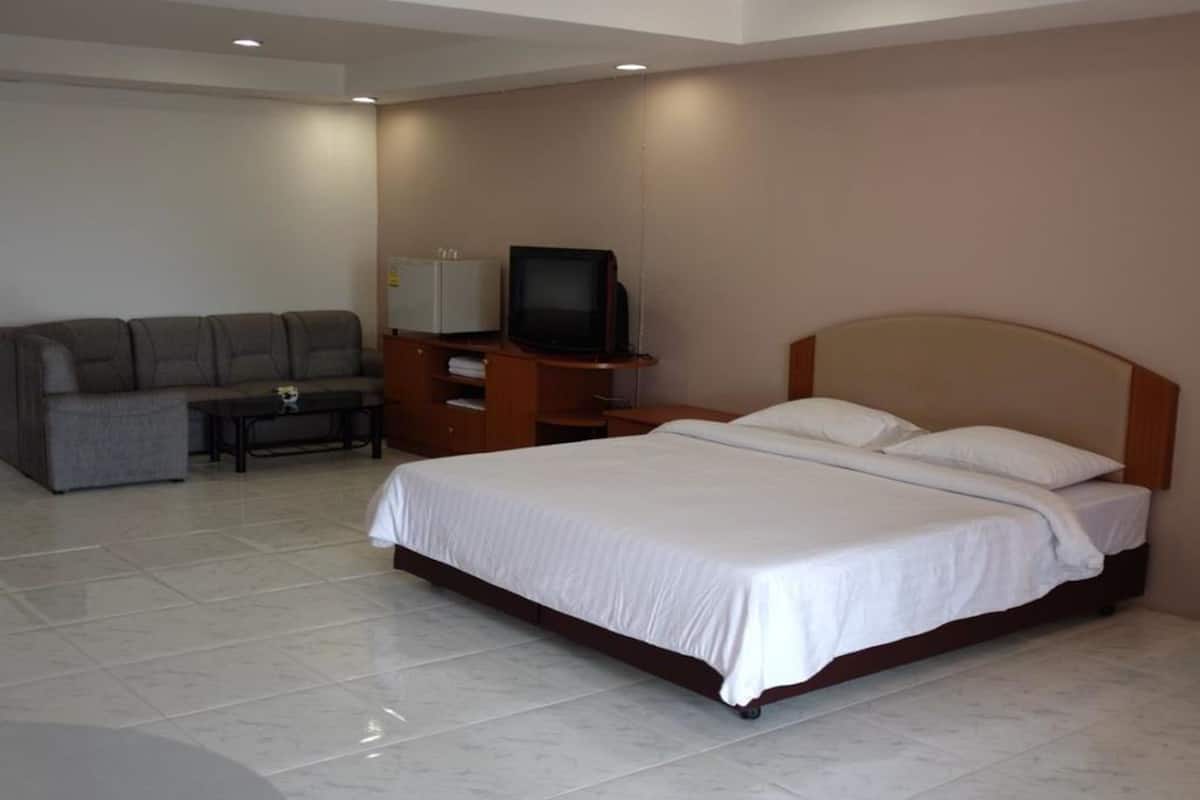 Una habitación de hotel con cama, sofá, televisión y una mesita.