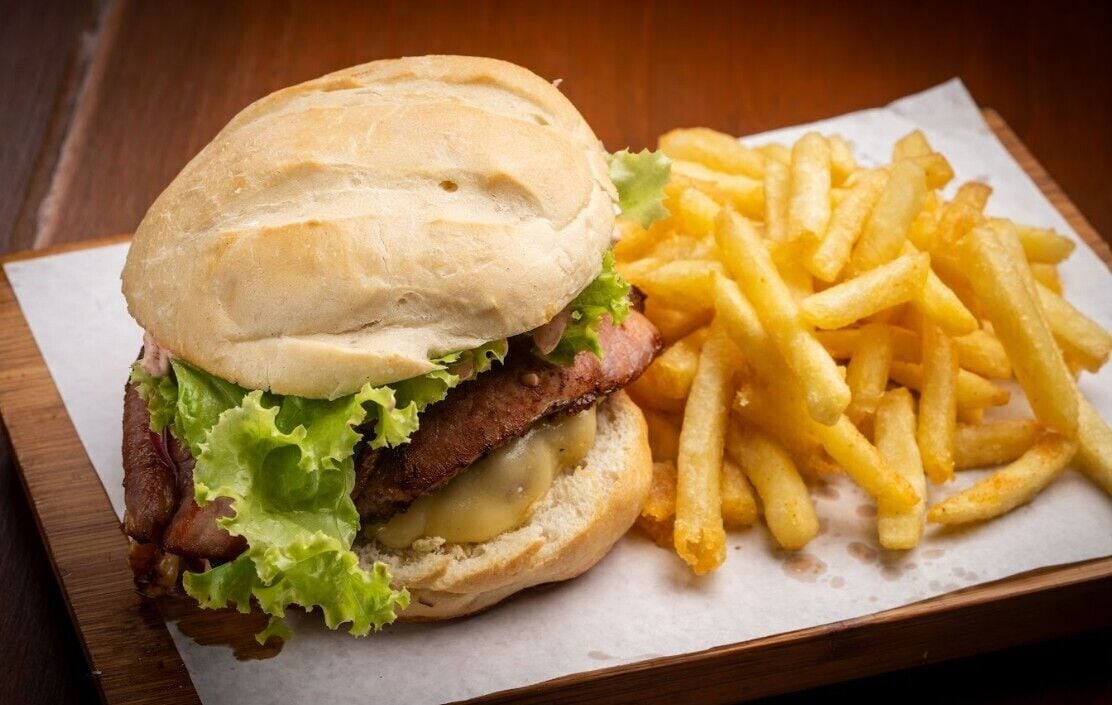 A burger with lettuce and a side of French fries on a wooden table.