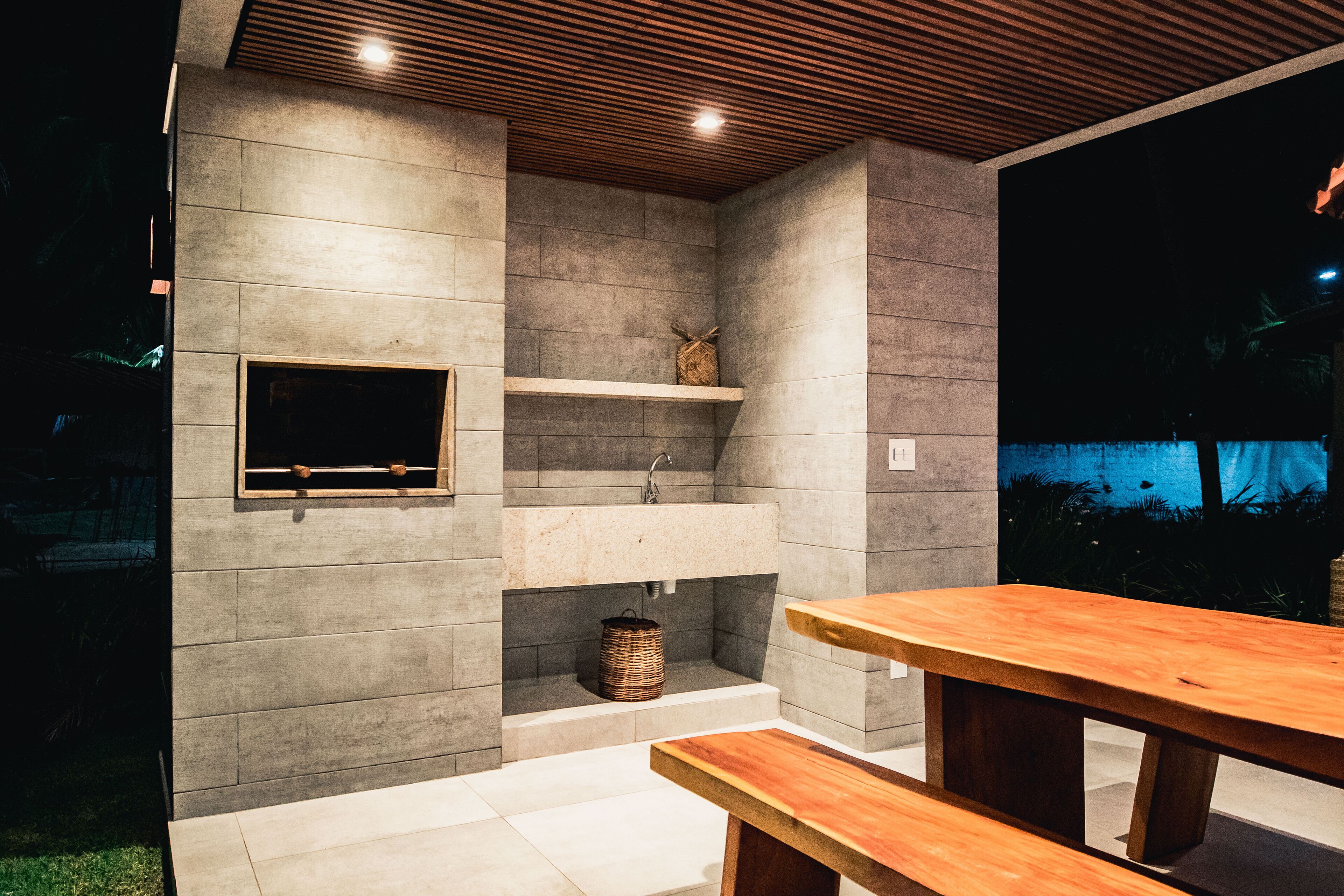 Ein moderner Küchenbereich im Freien mit integriertem Spülbecken, Holzböden und einem Holztisch.