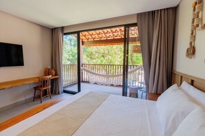 A hotel room with a large bed, a wooden chair, a small table, a TV mounted on the wall, and a balcony with a hammock. - Costa Dourada Village (Maragogi)