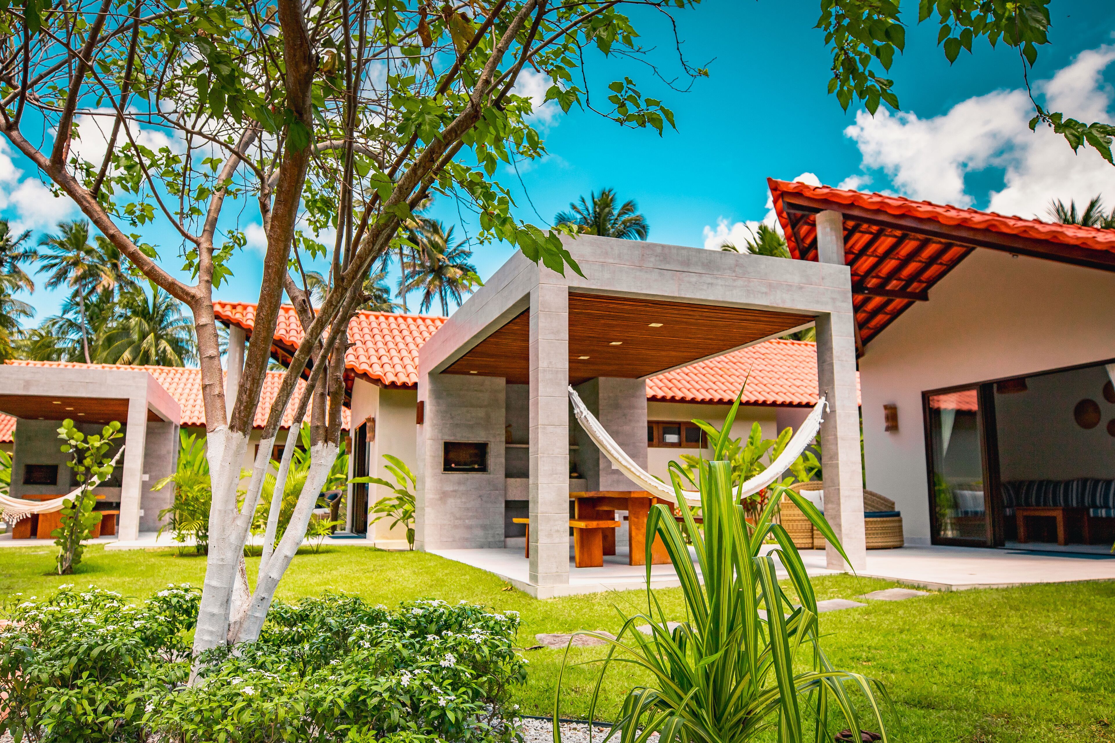 A modern house with a red-tiled roof, a hammock, and a well-maintained garden.