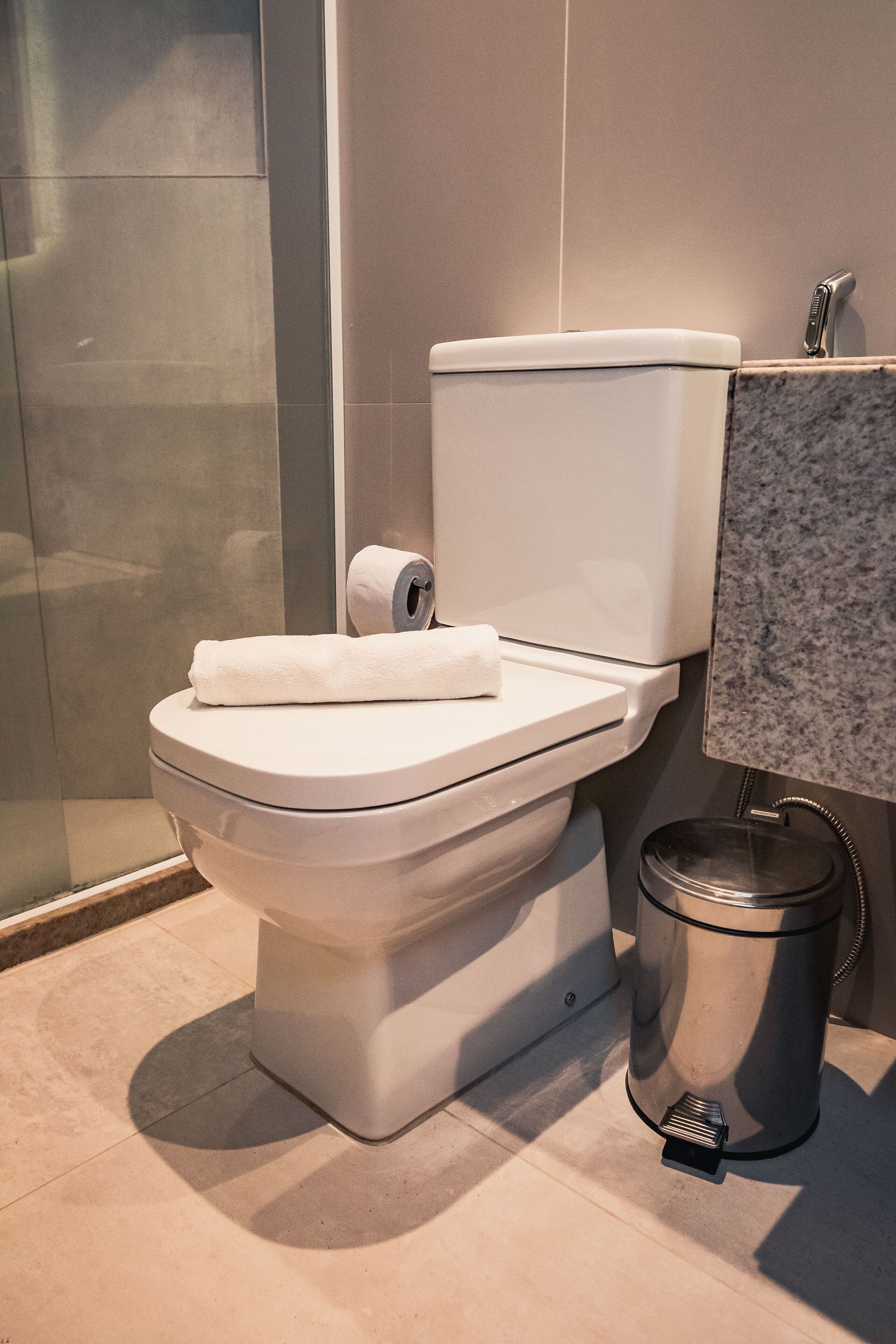 Un baño moderno con inodoro, cubo de basura y encimera de mármol.
